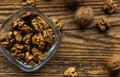 Walnut in a smale plate with scattered shelled nuts and whole nut which standing on a wooden vintage table. Walnuts is a