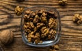 Walnut in a smale plate with scattered shelled nuts and whole nut which standing on a wooden vintage table. Walnuts is a