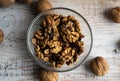 Walnut in a smale plate with scattered shelled nuts and whole nut which standing on a wooden vintage table. Walnuts is a