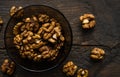 Walnut in a smale plate with scattered shelled nuts and whole nut which standing on a wooden vintage table. Walnuts is a