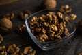 Walnut in a smale plate with scattered shelled nuts and whole nut which standing on a wooden vintage table. Walnuts is a