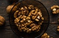 Walnut in a smale plate with scattered shelled nuts and whole nut which standing on a wooden vintage table. Walnuts is a