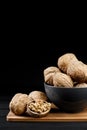 Walnut and walnut kernels on the plate on rustic wooden black background. Royalty Free Stock Photo