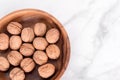 Walnus  in wooden bowl on light marble background with copy space. Flatlay, top view. Wooden plate with walnuts. Space for text. Royalty Free Stock Photo