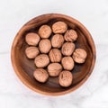 Walnuts in wooden bowl on light marble background. Flatlay, top view. Wooden plate with walnuts. Space for text. Organic food, Royalty Free Stock Photo