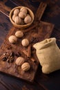 Walnuts in a bowl, cinnamon, star anise, coffee beans, and small bag on wooden cutting board. Nuts and spices on the Royalty Free Stock Photo