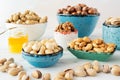 Walnuts, cashews, almonds and hazelnuts in beautiful bowls blue, white, green stand a white background.