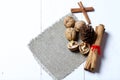 Walnuts, cinnamon sticks and fir cone. Lying on a piece of linen. Against the background of white painted boards