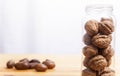 Walnuts glass jar and pecan over wooden surface