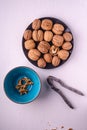 Walnuts heap food with half peeled nut in black plate near to vintage nutcracker and blue bowl on white background