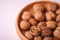 Walnuts heap food in wooden bowl on white background with half peeled nut
