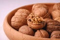 Walnuts heap food in wooden bowl on white background with half peeled nut