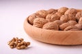 Walnuts heap food in wooden bowl on white background near to peeled nuts