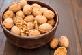 Walnuts lie in a bowl, next to them are chopped nuts on a wooden floor Royalty Free Stock Photo