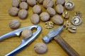 Walnuts, nutcracker and old hammer on wooden background. Close-up.