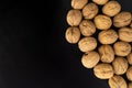 Walnuts in shell on black surface, top view. Background of round walnuts. Healthy nuts and seeds composition. Royalty Free Stock Photo