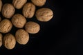 Walnuts in the shell on black surface, top view. Background of round walnuts. Healthy nuts and seeds composition. Royalty Free Stock Photo