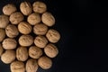 Walnuts in shell on black surface, top view. Background of round walnuts. Healthy nuts and seeds composition. Royalty Free Stock Photo