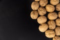 Walnuts in shell on black surface, top view. Background of round walnuts. Healthy nuts and seeds composition. Royalty Free Stock Photo