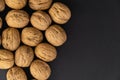 Walnuts in shell on black surface, top view. Background of round walnuts. Healthy nuts and seeds composition. Royalty Free Stock Photo