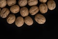 Walnuts in the shell on black surface, top view. Background of round walnuts. Healthy nuts and seeds composition. Royalty Free Stock Photo