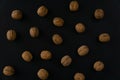 Walnuts in the shell on black surface, top view. Background of round walnuts. Healthy nuts and seeds composition. Royalty Free Stock Photo