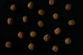 Walnuts in the shell on black surface, top view. Background of round walnuts. Healthy nuts and seeds composition. Royalty Free Stock Photo