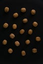 Walnuts in the shell on black surface, top view. Background of round walnuts. Healthy nuts and seeds composition. Royalty Free Stock Photo