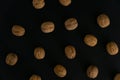 Walnuts in the shell on black surface, top view. Background of round walnuts. Healthy nuts and seeds composition. Royalty Free Stock Photo