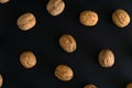 Walnuts in the shell on black surface, top view. Background of round walnuts. Healthy nuts and seeds composition. Royalty Free Stock Photo