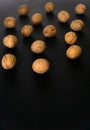 Walnuts in the shell on black surface, top view. Background of round walnuts. Healthy nuts and seeds composition. Royalty Free Stock Photo