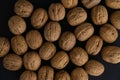 Walnuts in the shell on black surface, top view. Background of round walnuts. Healthy nuts and seeds background. Royalty Free Stock Photo