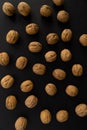 Walnuts in the shell on black surface, top view. Background of round walnuts. Healthy nuts and seeds background. Royalty Free Stock Photo