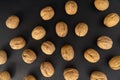 Walnuts in the shell on black surface, top view. Background of round walnuts. Healthy nuts and seeds background. Royalty Free Stock Photo