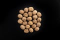 Walnuts in shell in the center on black surface, top view. Background of round walnuts. Healthy nuts and seeds Royalty Free Stock Photo