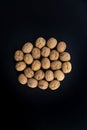 Walnuts in shell in the center on black surface, top view. Background of round walnuts. Healthy nuts and seeds Royalty Free Stock Photo