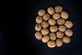 Walnuts in shell in the center on black surface, top view. Background of round walnuts. Healthy nuts and seeds Royalty Free Stock Photo