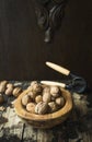 Walnuts with and without shell in a wooden bowl on a wooden rustic background with tongs for cracking nuts