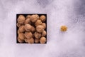 Walnuts on a square plate on bright textured surface, top view. Healthy nuts and seeds composition. Royalty Free Stock Photo