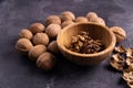 Walnuts in wooden bowl and on black slate surface. Healthy nuts and seeds composition. Royalty Free Stock Photo