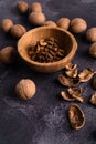 Walnuts in wooden bowl and on black slate surface. Healthy nuts and seeds composition. Royalty Free Stock Photo