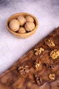 Walnuts in wooden bowl and on wooden carved board on bright textured surface. Healthy nuts and seeds composition. Royalty Free Stock Photo