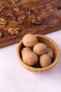 Walnuts in wooden bowl and on wooden carved board on bright textured surface. Healthy nuts and seeds composition. Royalty Free Stock Photo