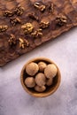 Walnuts in wooden bowl and on wooden carved board on bright textured surface. Healthy nuts and seeds composition. Royalty Free Stock Photo