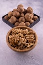 Walnuts in wooden bowl and on a square plate on bright textured surface, top view. Healthy nuts and seeds composition. Royalty Free Stock Photo