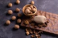 Walnuts in wooden bowl on wooden carved board. Walnuts, stone and cutting board. Healthy nuts and seeds composition.