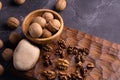 Walnuts in wooden bowl on wooden carved board. Walnuts, stone and cutting board. Healthy nuts and seeds composition.