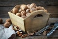 Walnuts in a wooden crate and nutcracker on wooden table.