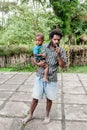 Wamena, Indonesia - January 9, 2010: Man with kid of the Dani tribe in a usual clothes standing in Dugum Dani Village.