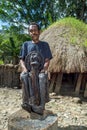 Old man in front of a traditional house showing off a mummy of a village elder Mummy